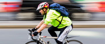 Male bike commuter zooms to work in brightly colored clothes and helmet